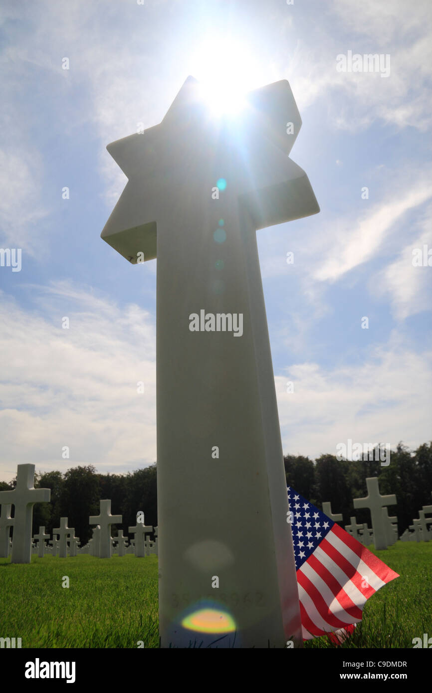 Die Sonne kriecht über den oberen Teil einer jüdischen Grabstein mit einer amerikanischen Flagge am Standort Luxembourg American Cemetery, Luxemburg. Stockfoto