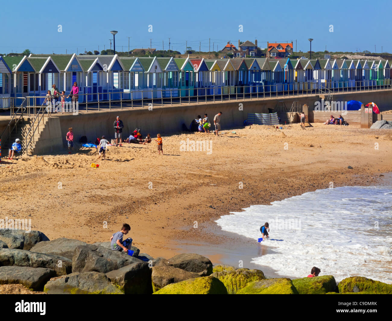 Southwold direkt am Meer im Sommer mit Wellen an den Strand und die traditionellen Strandhütten hinter Suffolk England UK Stockfoto