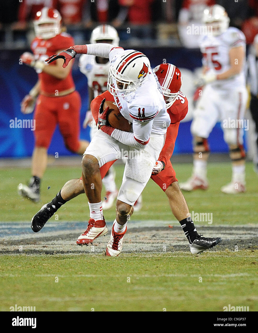 27.Dec 2011 - Charlotte, North Carolina; USA - University of Louisville Cardinals (11) JOSH CHICHESTER läuft die Fußball wie die North Carolina State Wolfpack konkurrieren gegen die University of Louisville Cardinals in der Belk Schüssel College-Football-Spiel, das die Bank of America Stadium stattfand Stockfoto