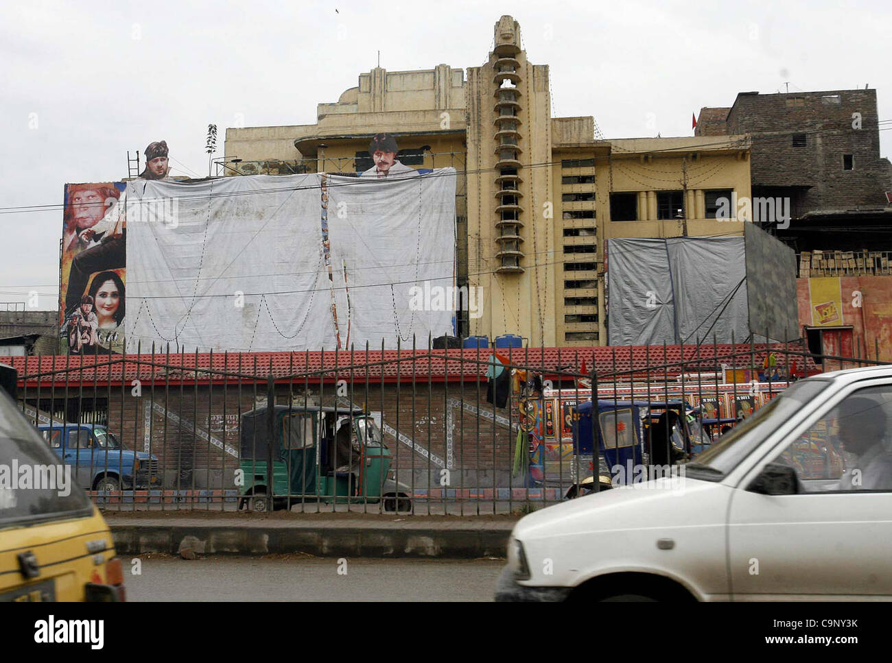 Autofahrer fahren durch ein Kino Haus wo Plakate von Filmen mit Tüchern im Respekt der Jashan-e-Eid Milad-un-Nabi (SAW) am GT.road in Peshawar auf Freitag, 3. Februar 2012 abgedeckt werden. Stockfoto