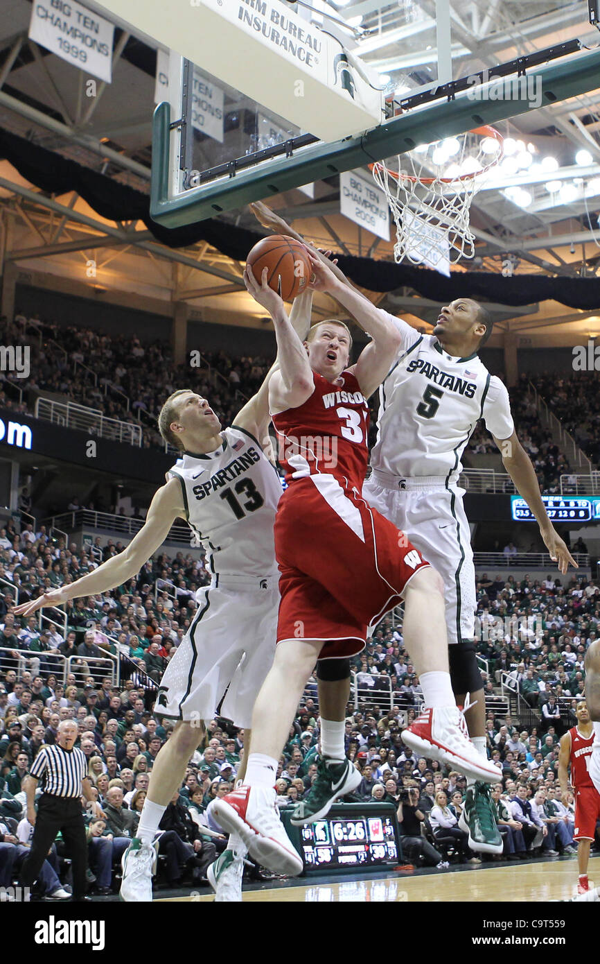 16. Februar 2012 - East Lansing, Michigan, USA - Wisconsin Badgers vorwärts Mike Bruesewitz (31) Laufwerke in den Warenkorb legen, wie er von Michigan State Spartans verteidigt wird bewachen Austin Thornton (13) und Michigan State Spartans center Adreian Payne (5) in der Mitte Breslin. MSU besiegte Wisconsin 69-5 Stockfoto