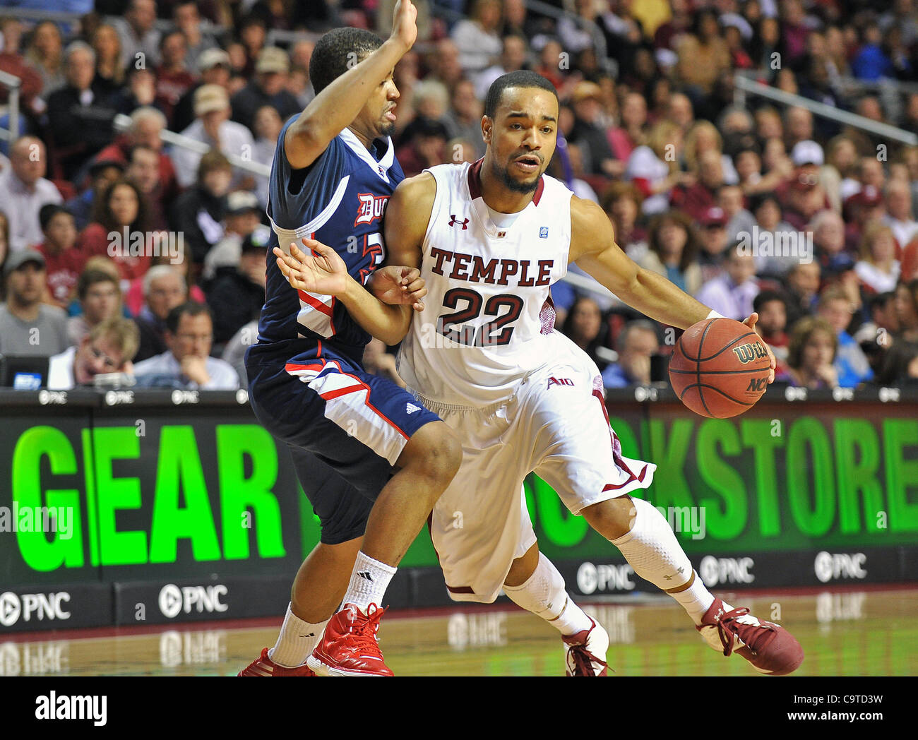 18. Februar 2012 - Philadelphia, Pennsylvania, USA - Tempel Eulen schützen Aaron Brown (22) Laufwerke in den Korb, bewacht von Duquesne Dukes Guard Eric Evans (3) bei den NCAA-Basketball-Spiel zwischen den Tempel Eulen und die Duquesne Dukes im Liacouras Center in Philadelphia. Tempel führt Duquesne 42-3 Stockfoto