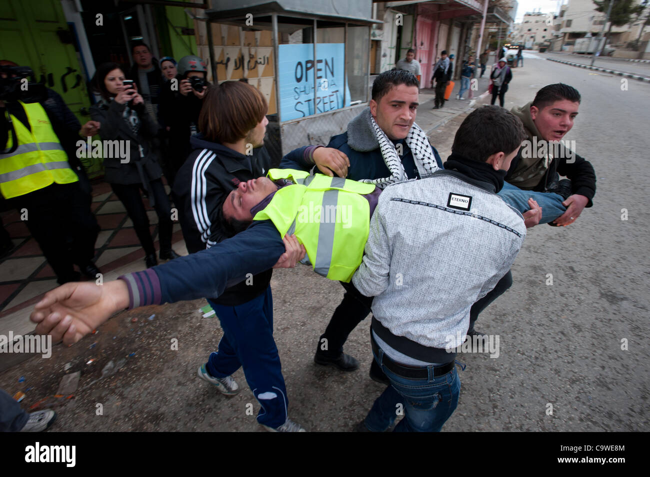 HEBRON, besetzten palästinensischen Gebieten - 24 Februar: Palästinenser tragen einen Kameraden zu überwinden durch Tränengas bei Demonstrationen zum Gedenken an einer tödlichen Schießerei durch eine israelische Siedler in der Moschee Al-Ibrahimi und Aufruf zur Eröffnung der Shuhada Straße, die nach dem Angriff geschlossen wurde. Stockfoto