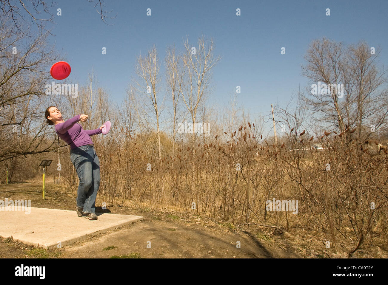 London Ontario, Kanada - 14. März 2012. Meg Jarvis ' Abschlag der während eines Spiels der Disc-Golf auf dem 18 Disc Golf Course befindet sich in St. Julien Park in East London. London ist der Golfplatz und eine Liga, die in den wärmeren Monaten Samstagmorgen konkurriert. Die Regeln sind ähnlich wie tradi Stockfoto