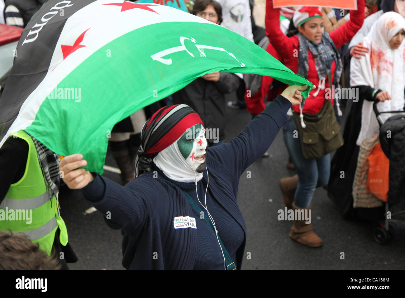 LONDON, UK, 17. März 2012. Ein Anti hält beim marschieren von Paddington Green an ihre Botschaft auf den Jahrestag des Aufstands zum protest gegen die herrschenden Assad-Regime und die aktuellen Themen in Syrien Assad Unterstützer der syrischen Flagge über dem Kopf. Stockfoto