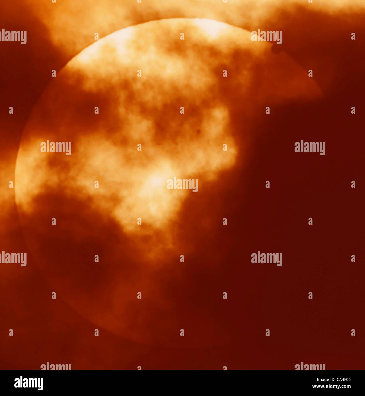 Ein seltene Venus-Transit der Sonne am 6. Juni 2012 fotografiert durch Wolke aus London, UK am 05:42, mit Sonnenflecken auch sichtbar in Richtung Mitte des Datenträgers. Venus ist rechts in der Nähe von Rand der Sonnenscheibe sichtbar oben. Stockfoto