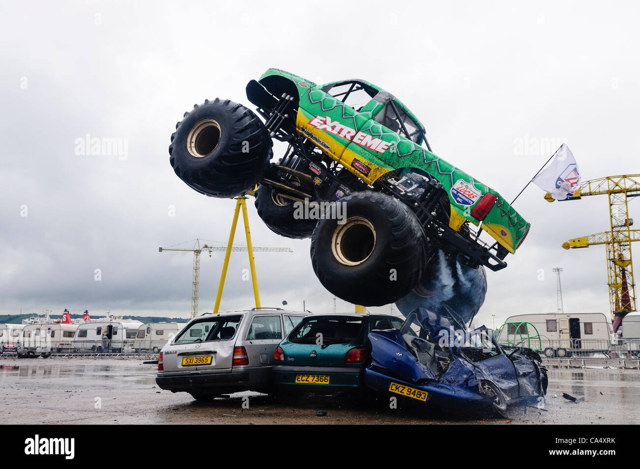 Monstertruck zerquetscht und springt über drei Autos auf der Extreme Stunt Show Stockfoto