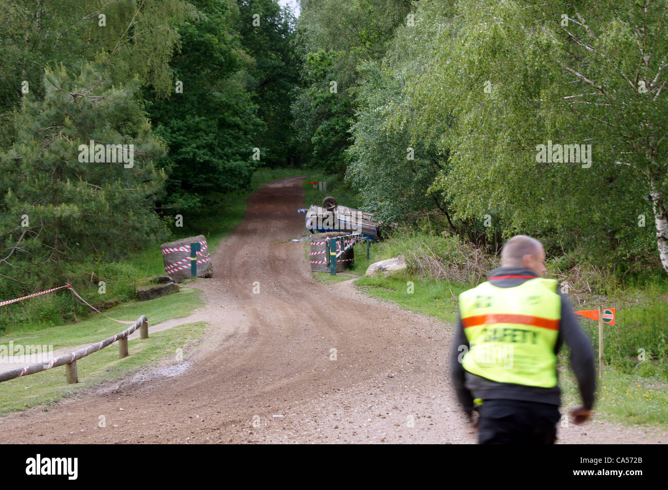 Sicherheit Marschall läuft der Peugeot 309, angetrieben von Nigel Hunt mit Andy Wright als Beifahrer die stürzte nach der Kollision mit einer Furche am Wald verfolgen vor 18 auf der Sherwood-Kiefern-Bühne. Stockfoto