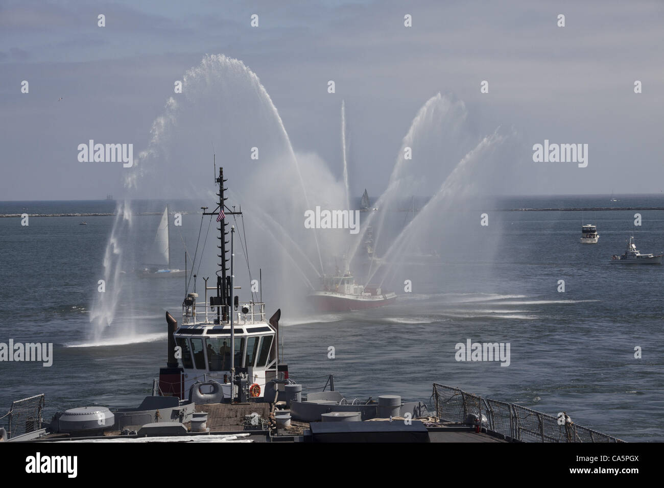 Schlepper liefern Strom und LA City Fire Boote bieten Fanfare Brunnen für die letzte Reise des Schlachtschiffs USS Iowa vom Liegeplatz 51 zu seinem neuen Haus am Liegeplatz 87 in San Pedro, Los Angeles, Kalifornien, wo es als Museumsschiff im Juli 2012 eröffnet. Stockfoto