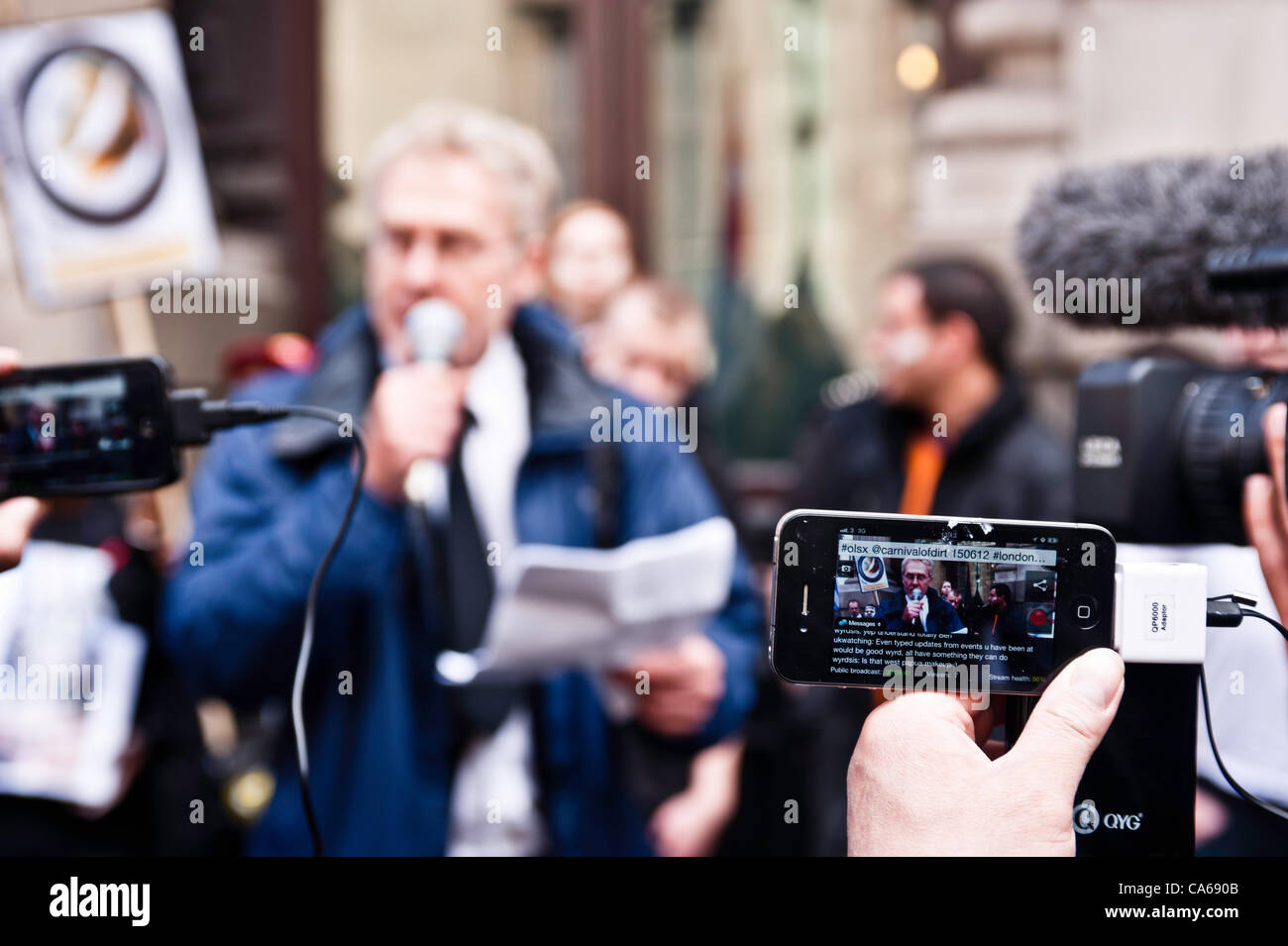 London, UK - 15. Juni 2012: ein Mann, die Dreharbeiten auf dem iPhone während der Karneval von Schmutz. Mehr als 30 Aktivisten-Gruppen aus London und auf der ganzen Welt haben sich zusammengeschlossen, um die angeblichen illegalen Taten von Bergbau und Gewinnung Unternehmen hervorzuheben. Stockfoto