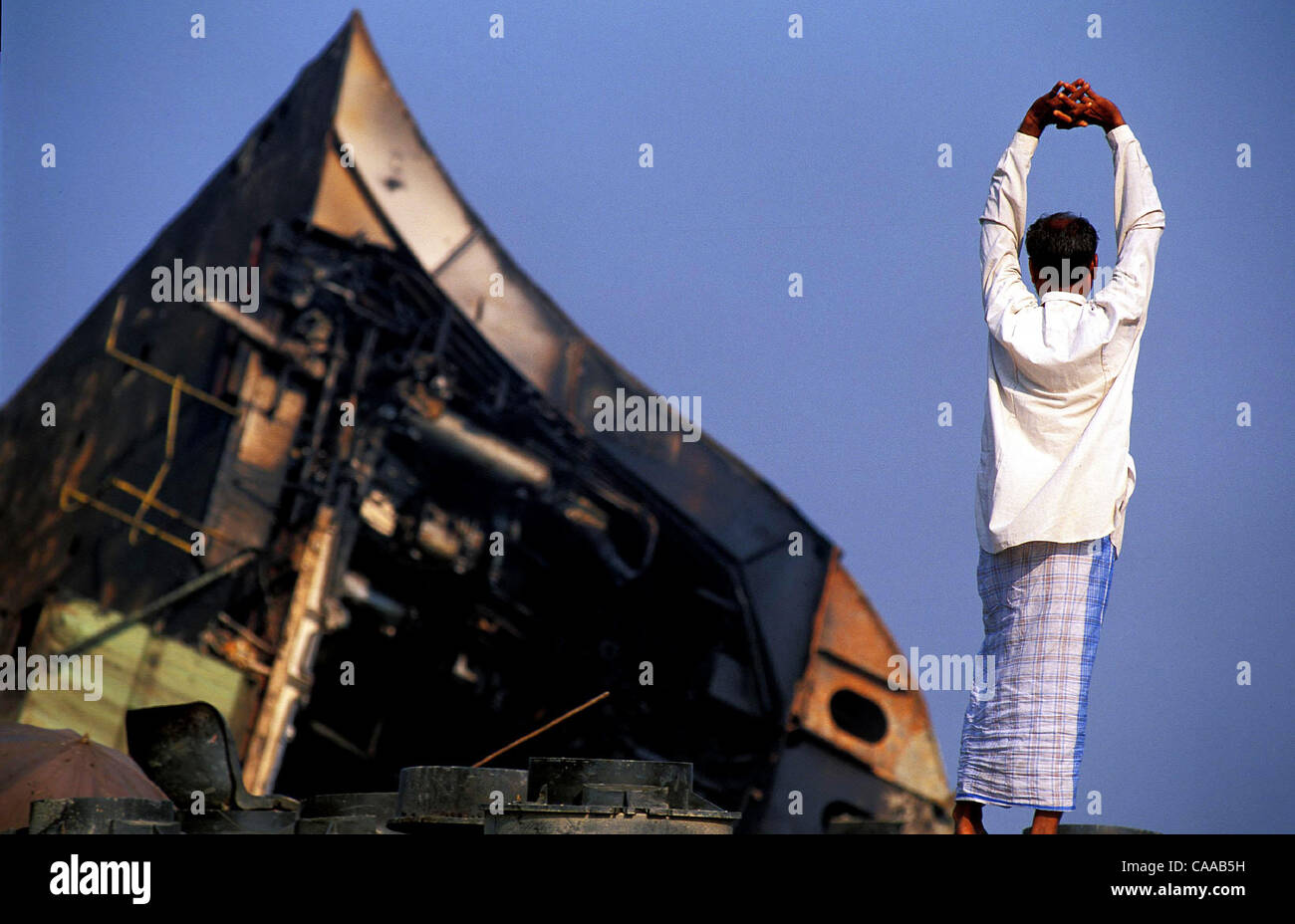 CHITTAGONG, Bangladesch, Shipwrecking 13. Januar 2003.  Vorarbeiter erstreckt sich als Blick auf den Rumpf des teilweise geborgenen Supertanker.  Foto von Chris Stowers/JiwaFoto Stockfoto