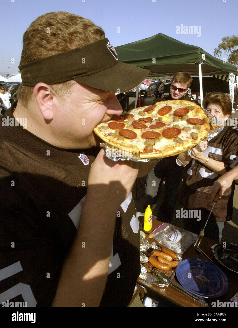 Mike Cuneo, Modesto, nimmt einen Bissen von der Wurst und Salami Pizza während einer Heckklappe Party im Oakland Coliseum Sonntag Januar 19,2003. (Contra Costa Times / Bob Larson) 2003 Stockfoto