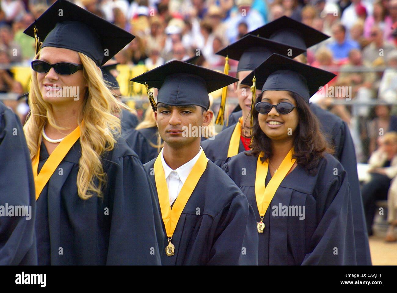 Absolventinnen und Absolventen der verschiedensten ethnischen Arten warten in der Schlange, ihre Diplome erhalten. Stockfoto