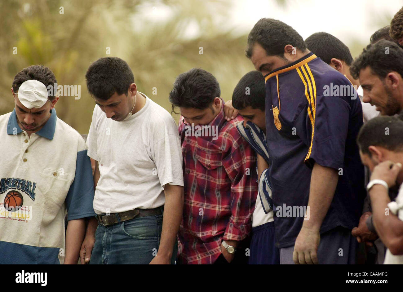 (Veröffentlicht 21.04.2003, a-4): NC Bagdad X015... 18. April 2003, Bagdad, Irak...  Freiwillige, die sich aus den Geruch von verwesenden Körper zu schützen sehen Sie wie die anderen unten Hilfe Escavate einen menschlichen Körper (Fuß und Bein), der in ein Civilain Auto bleibt, die in der Mitte t gefangen wurde Stockfoto