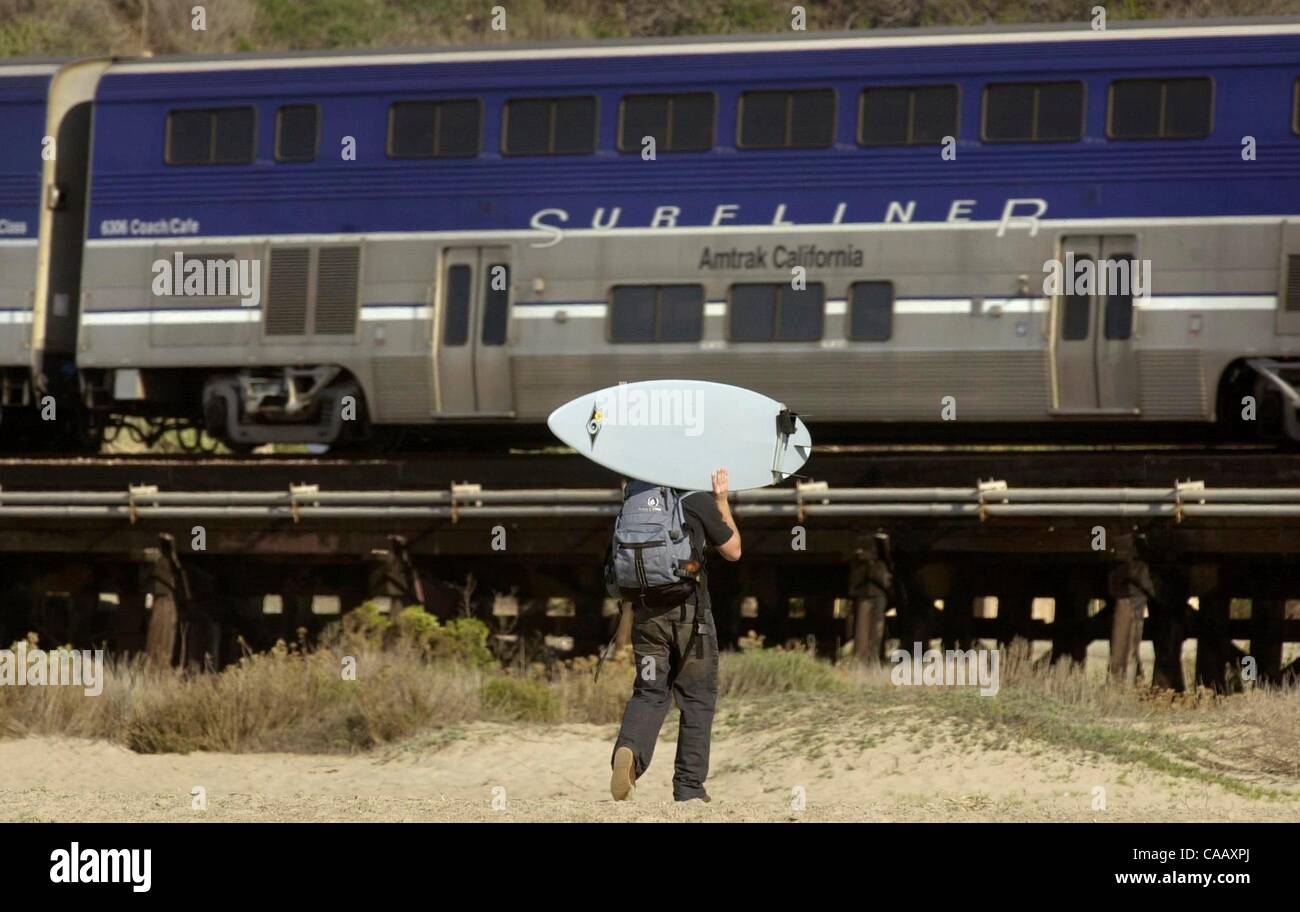 (Veröffentlichte 14.02.2005, a-12) Am Strand von Böcken vergeht ein Personenzug Amtrak als Surfer (keine I.D.) mit seinem Brett auf den Pfad, der unter der Railroad Trestle vergeht.  U/T Foto CHARLIE NEUMAN Stockfoto