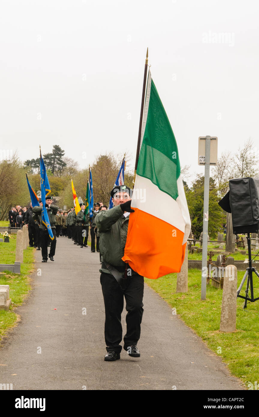 Männer, gekleidet in paramilitärischen Uniformen, und Vertreter der Sinn Féin, der politische Flügel der Irisch-Republikanischen Armee (IRA), halten Sie die Irische trikolore Flaggen während der jährlichen Ostern steigende Gedenken, Belfast, Nordirland. Stockfoto