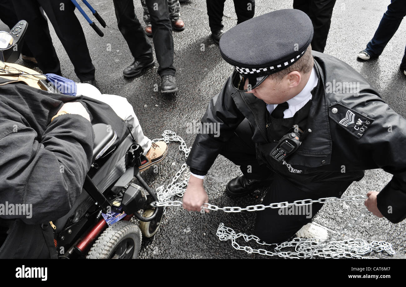 18.04.12, London, UK: ein Polizist entfernt Ketten aus einem Rollstuhl, da Behinderte Demonstranten Straßen am Trafalgar Square auf Fragen eingehen, sie konfrontiert sind, Inclluding Änderungen der Leistungen bei Erwerbsunfähigkeit blockieren. Stockfoto