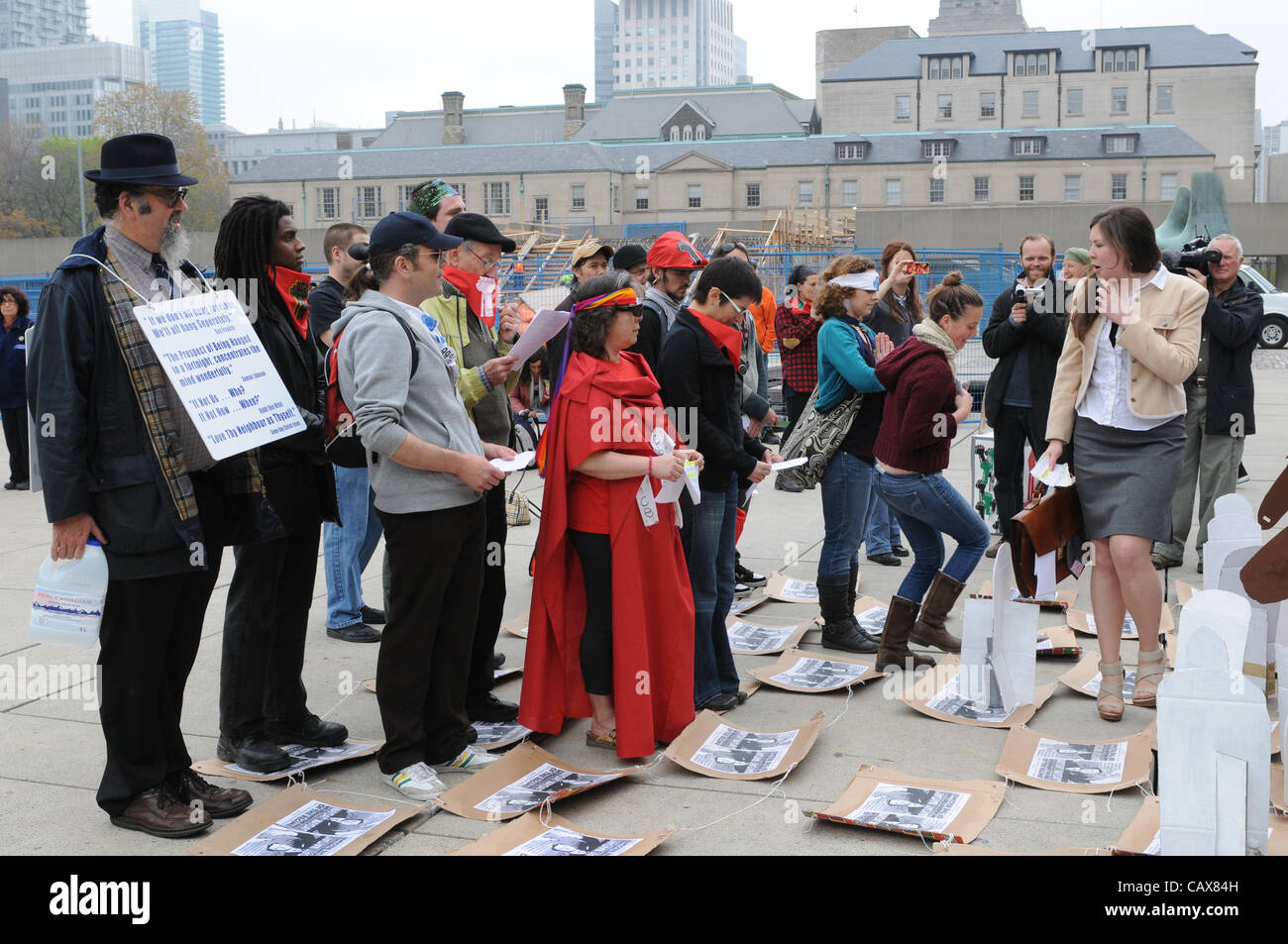 1. Mai 2012, eine kleine Gruppe von Toronto Demonstranten besetzen erlassen ein Stück Straßentheater basierend auf die Bewegung der Figuren auf einem Schachbrett an Nathan Philips Square, Rathaus, Toronto, Ontario, Kanada. Stockfoto