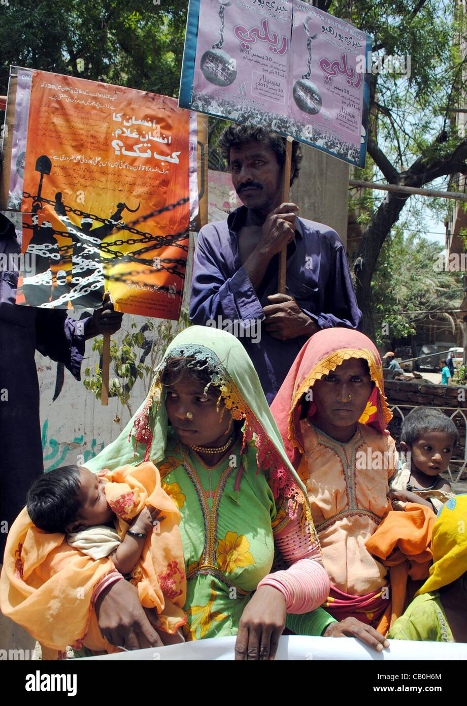 Bauern, die vor kurzem von einem privaten Gefängnis ein Vermieter befreit wurden, halten Plakate, wie sie protestieren gegen geklebte labouring in Hyderabad auf Dienstag, 15. Mai 2012. Stockfoto