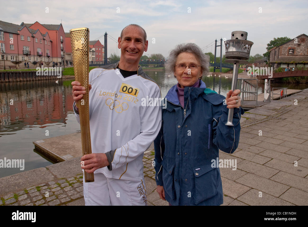 Penny Elsom, Tochter von Commander Bill Collins, der 1948 London Olympic Torch Relay, organisiert, hält die 1956 Olympische Fackel & Fackelträger Paul Giblin hält die 2012 Olympische Fackel in Exeter Phase des Olympischen Fackellaufs Stockfoto