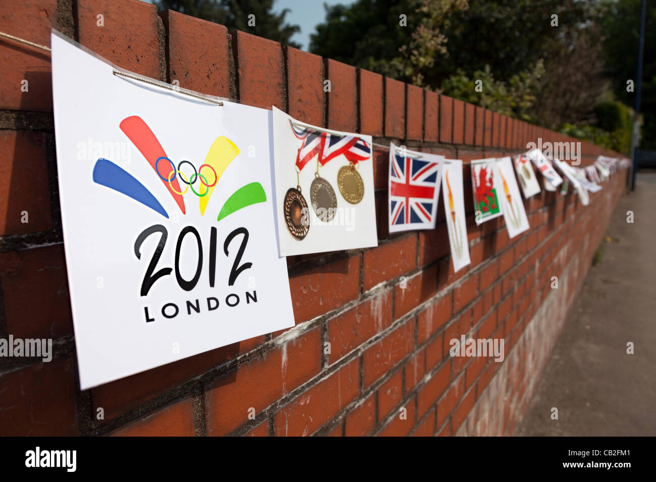 Flaggen und Wappen in Girlande auf einer roten Backsteinmauer auf der Strecke für die 2012 Olympischen Fackel laufen durch die Stadt Abergavenny, Wales, UK, statt auf Freitag, 25. Mai 2012. Bunting, wurde vor der Veranstaltung aufgestellt Stockfoto