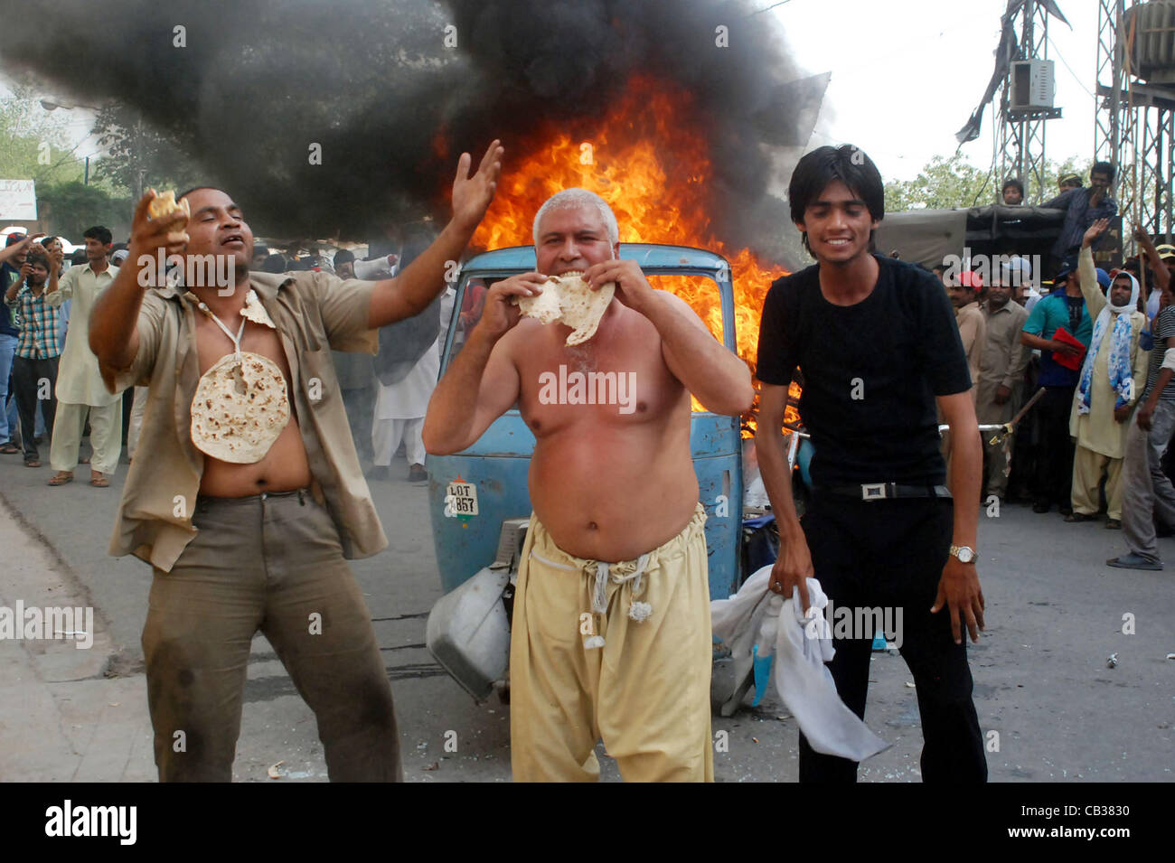 Alle Vereinsmitglieder in Pakistan CNG versammeln sich in der Nähe von brennenden Autorikscha Chant Parolen gegen Gas Lastabwurf bei Protestkundgebung am nördlichen Sui Gas Unternehmenszentrale in Lahore auf Montag, 28. Mai 2012. Stockfoto
