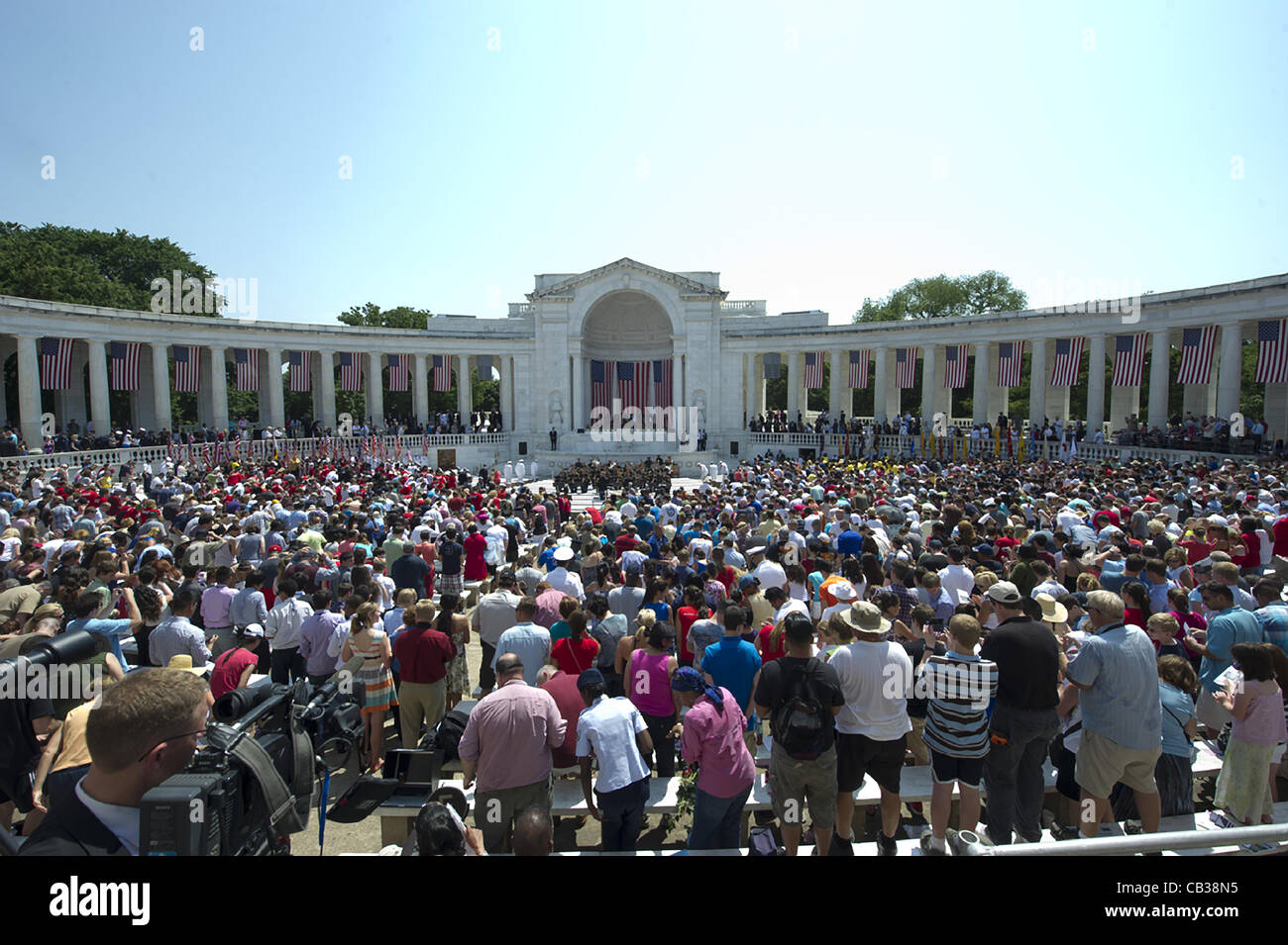 Beobachter im Amphitheater auf dem Arlington National Cemetery stehen für die Nationalhymne während während der Gedenktag Gottesdienste auf dem Arlington National Cemetery 28. Mai 2012 in Arlington, VA Stockfoto