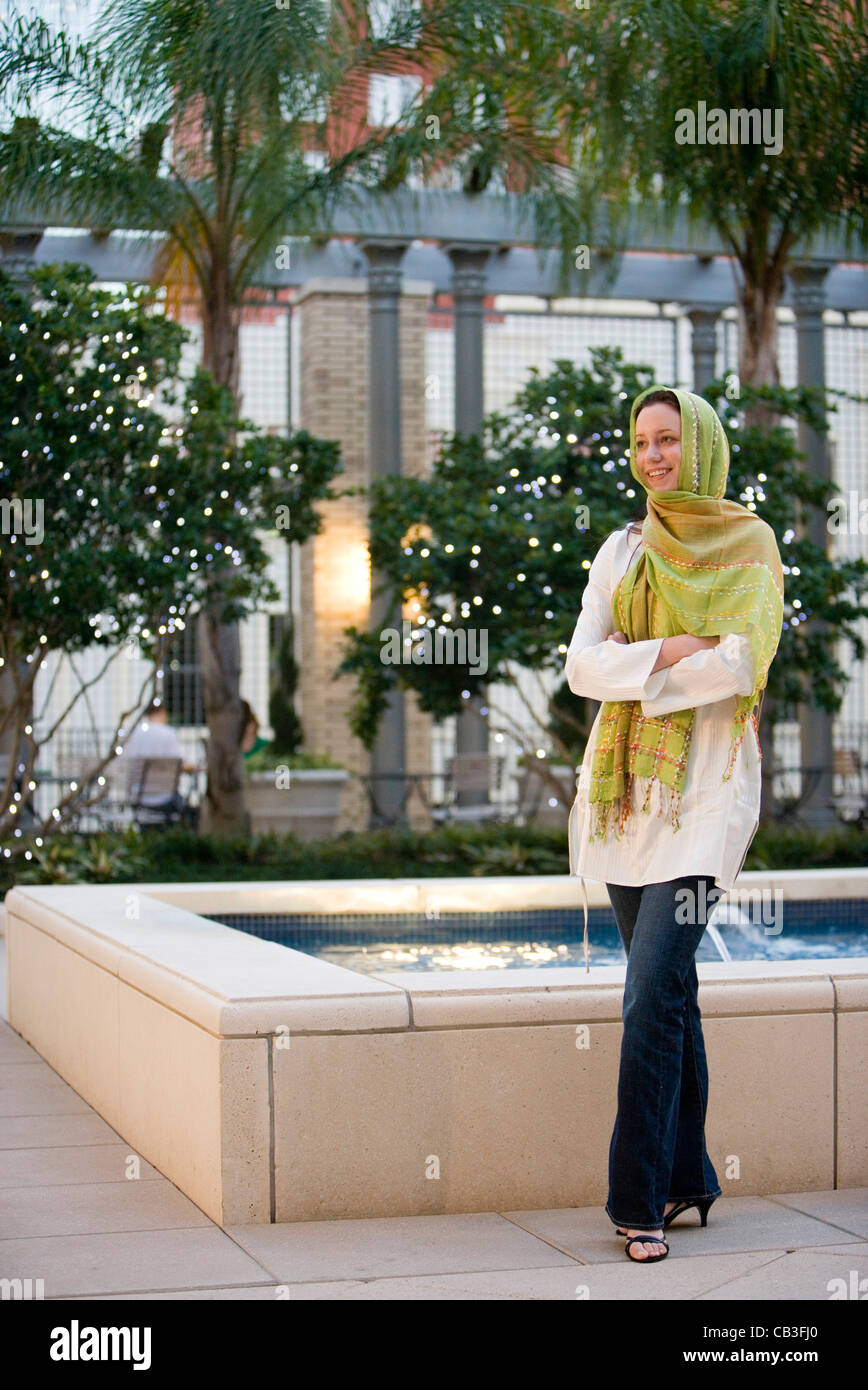 Junge Frau trägt ein Kopftuch steht von einem Brunnen außerhalb eines Gebäudes Stockfoto