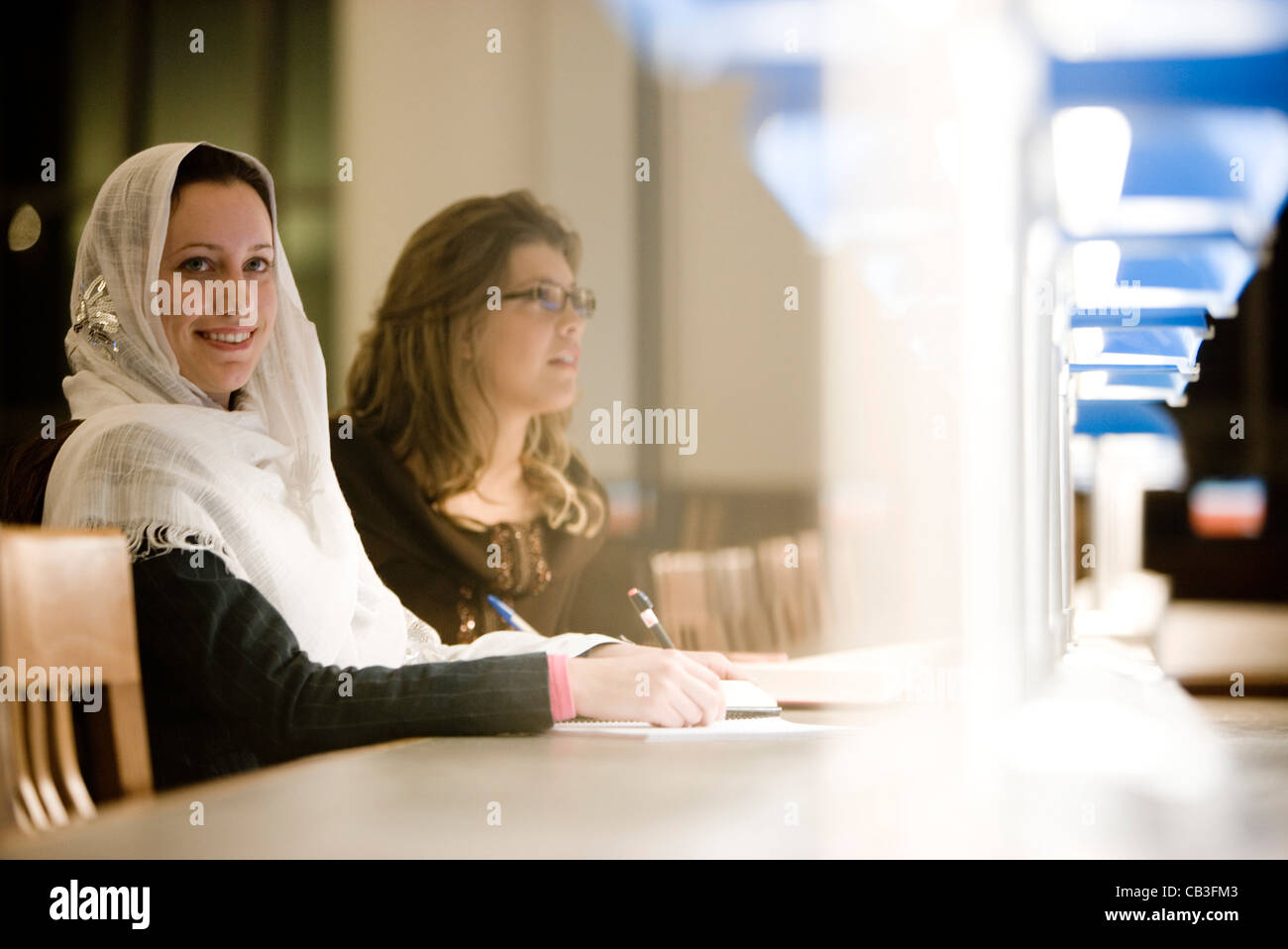 Zwei junge Frauen sitzen im Lesesaal einer Bibliothek Stockfoto