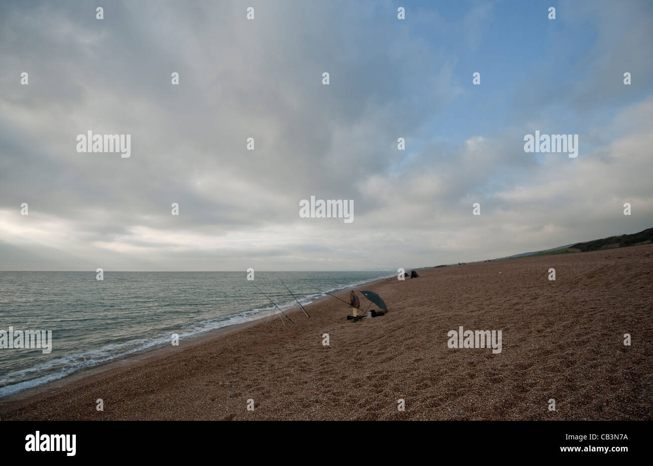 Angeln im Meer unter Herbst Himmel aus Chesil Beach in der Nähe von Abbotsbury in Dorset, eine 29 km lange Barriere Kiesstrand an der Südküste Stockfoto