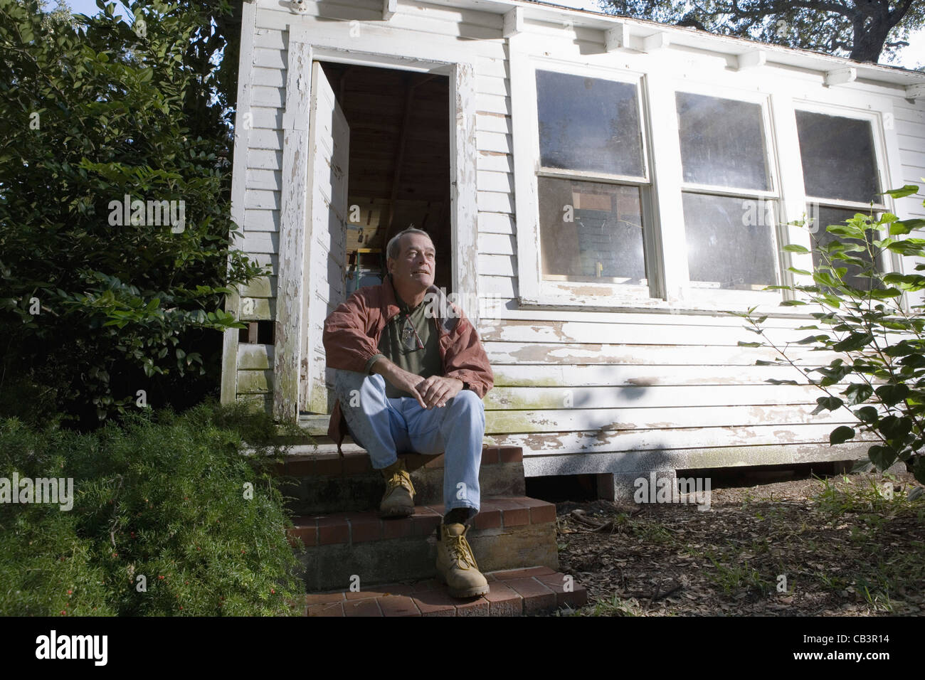 Reifer Mann sitzt vor der verfallenen Tool shed Stockfoto