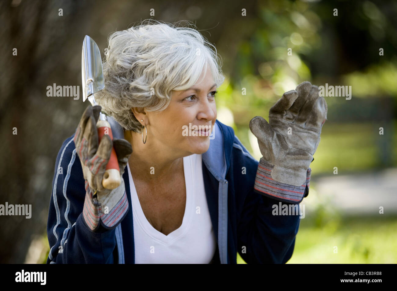 Nahaufnahme von Reife Frau mit Arbeitshandschuhen und hält ein Gartenarbeitwerkzeug Stockfoto