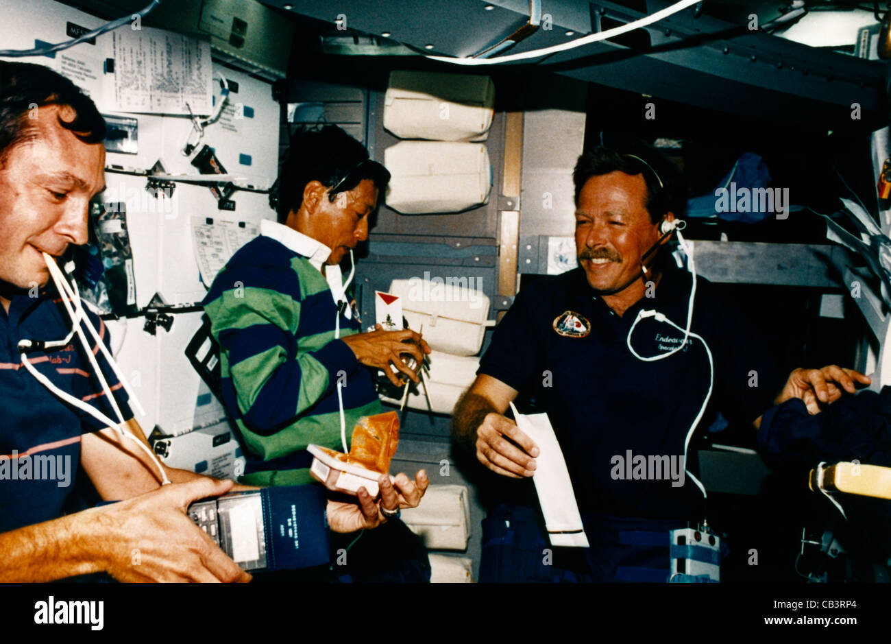 Astronauten Curtis Brown (Pilot), Mamoru Mohri (Payload Specialist und erster japanischer Astronaut an Bord des Shuttles) Robert L. Gibson (Commander) essen A Stockfoto