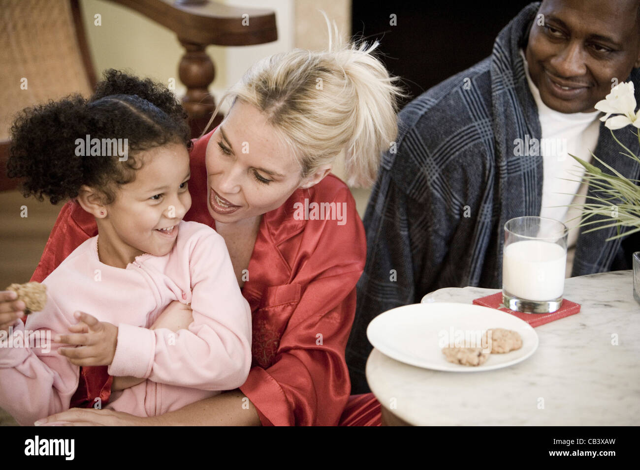 Inter-racial Familie mit Tochter gekleidet im Pyjama im Wohnzimmer sitzen Stockfoto
