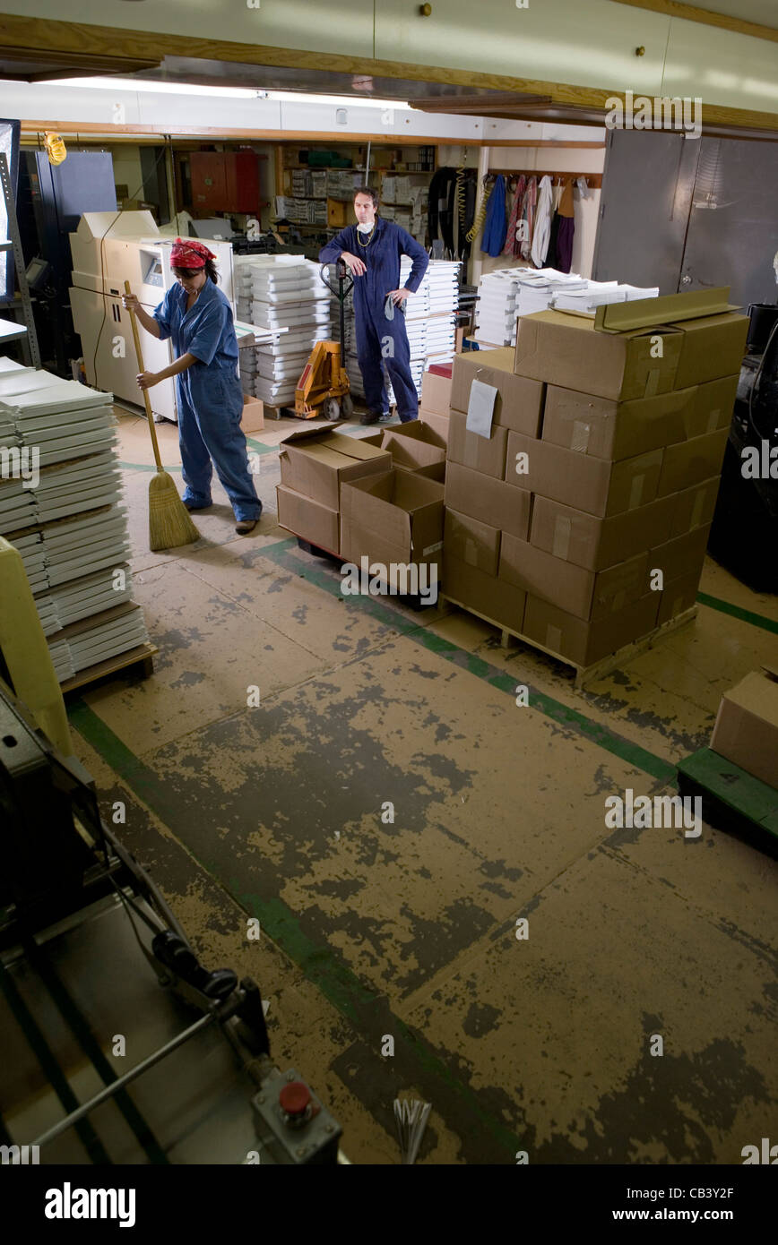 Porträt eines Mannes und einer Frau in Overalls arbeitet in einem Lager Stockfoto