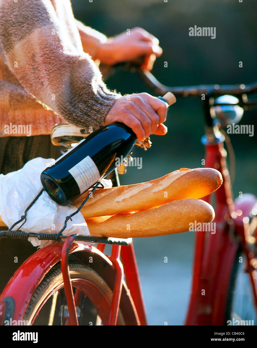 Dennoch: Mann mit Fahrrad, eine Flasche Rotwein in der Hand, Baguette auf Träger Stockfoto