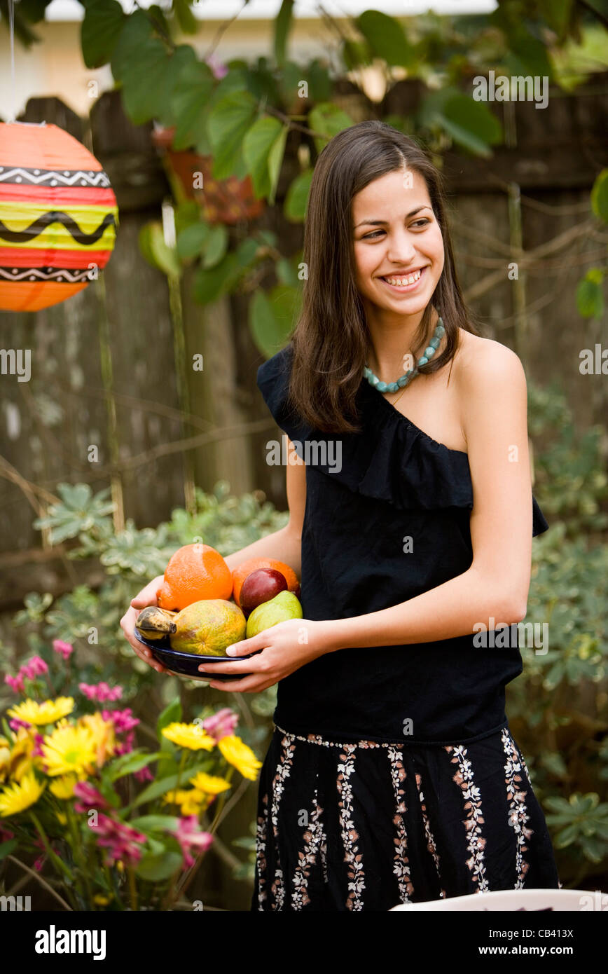Fröhliche junge Frau hält eine Schale mit Obst Stockfoto