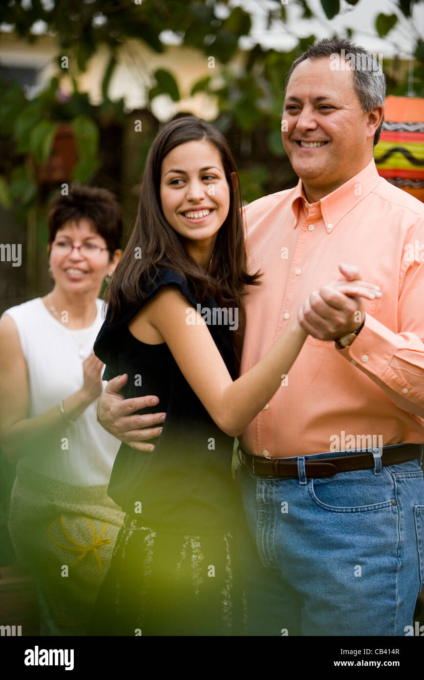 Blick auf reifer Mann tanzt mit seiner Tochter und seine Frau Jubel im Hintergrund Stockfoto
