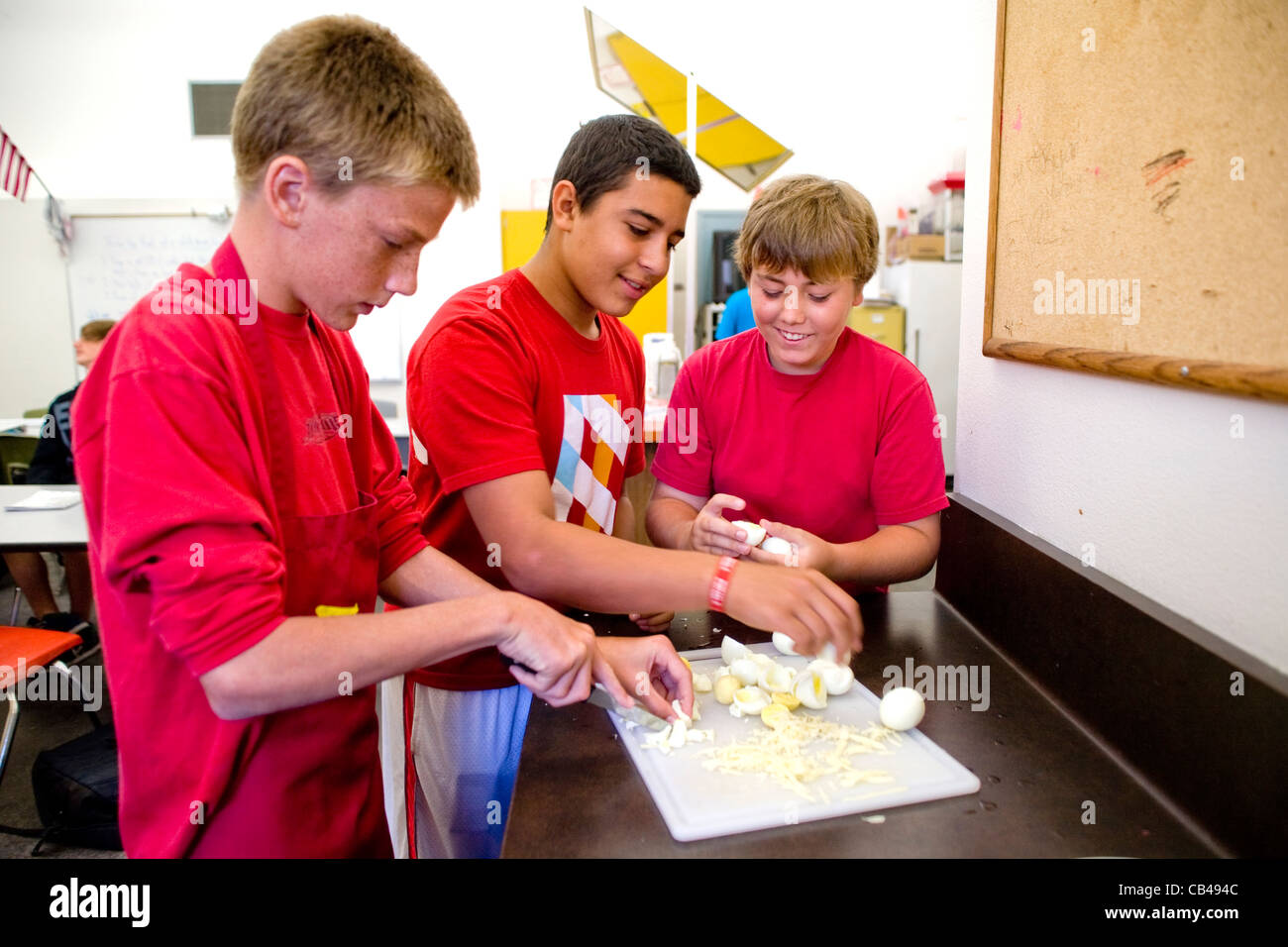 Kaukasische und Hispanic achten Klasse jungen an einer Mittelschule in Südkalifornien aufbrechen hartgekochten Eiern vorbereiten, Kochen Stockfoto