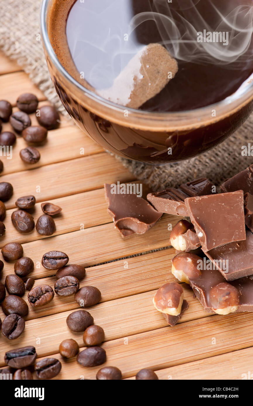 Tasse Kaffee, Schokolade mit Nüssen und Kaffeebohnen auf hölzernen Hintergrund mit Leinwand Stockfoto