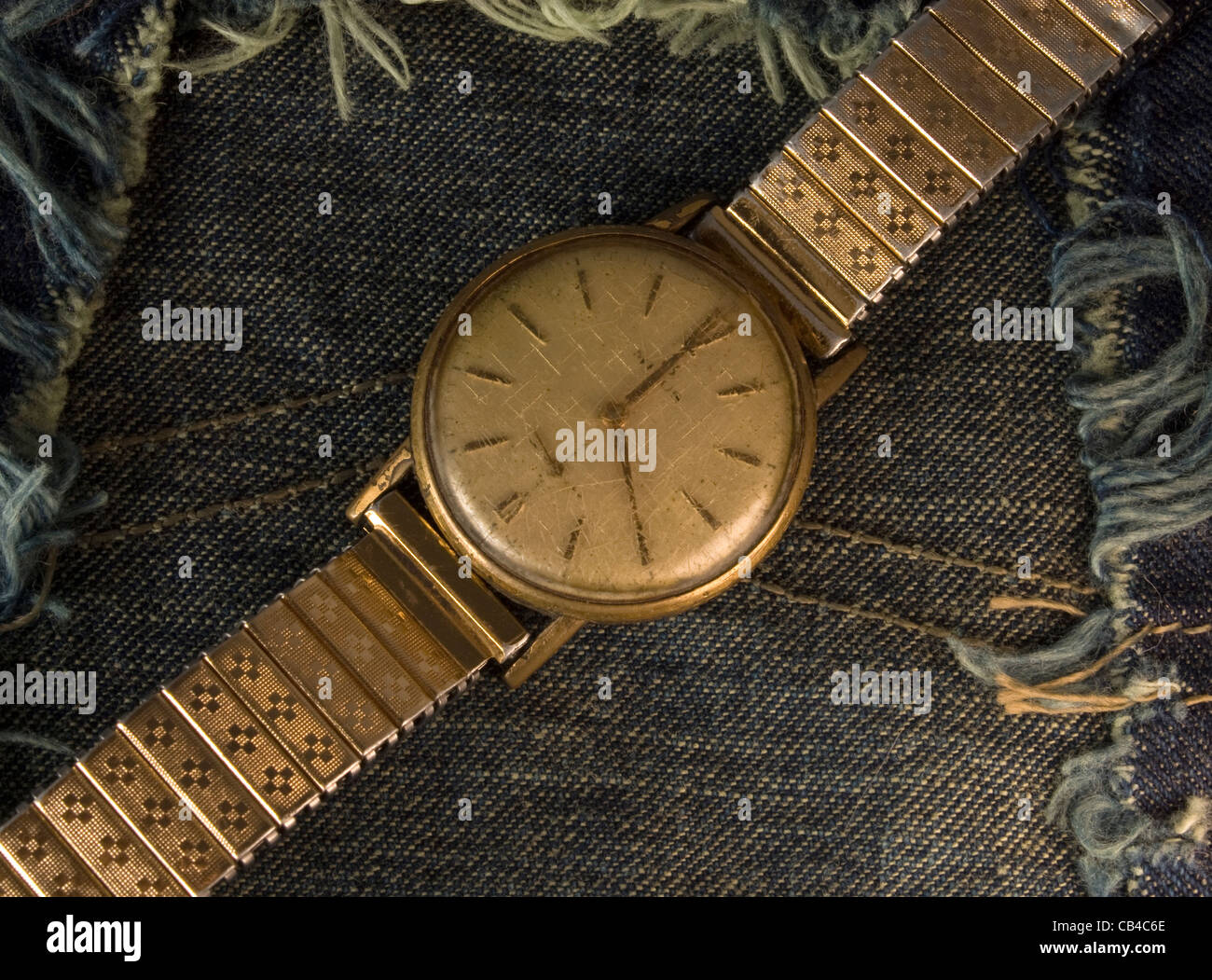 Retro-goldene Armbanduhr hautnah über blue-Jeans-Stoff-Hintergrund. Stockfoto