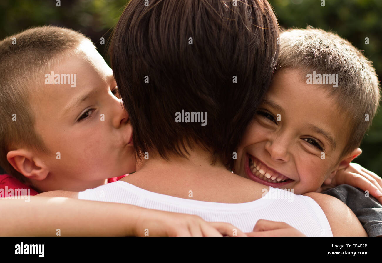 Zwei Brüder zeigen Liebe zu dort Mutter mit einem Kuscheln Und eine Kuss-Familie während des Lockdown Stockfoto