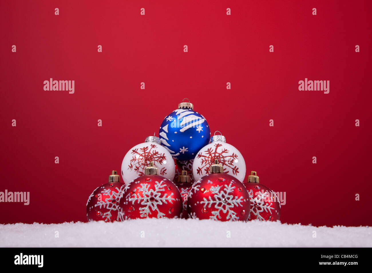 bunte Weihnachtskugeln über den Schnee mit einem roten Hintergrund (Tiefenschärfe) Stockfoto