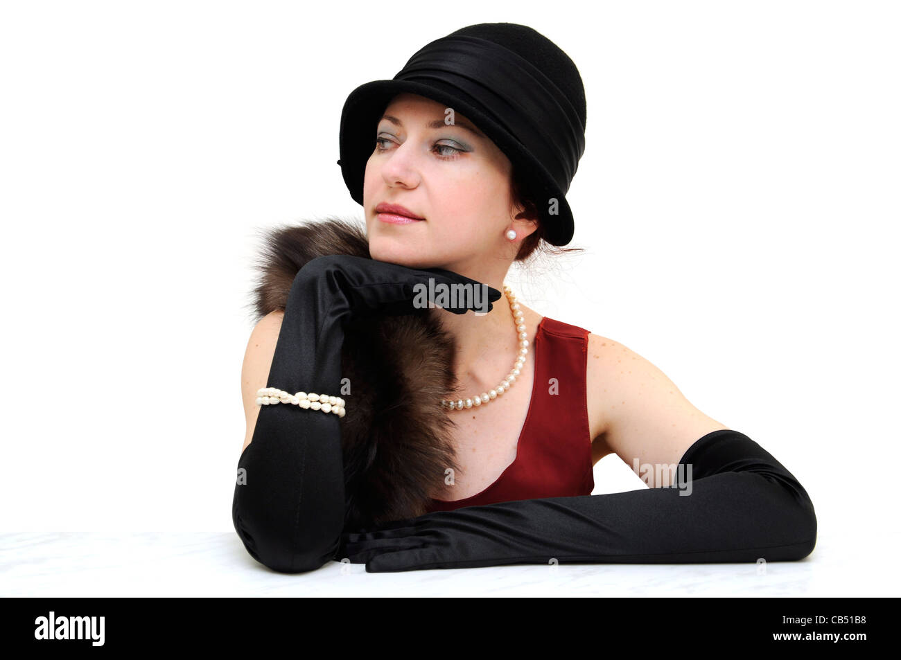 Junge schöne Dame in schwarz retro Hut und Handschuhe, tragen Perlenkette und Armband, sitzen und auf der Suche zur Seite. Stockfoto