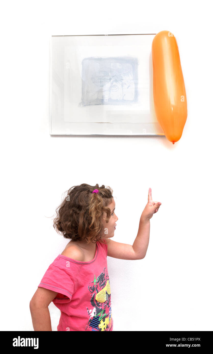 Junges Mädchen zeigt einen Ballon fest an der Wand durch statische Stockfoto