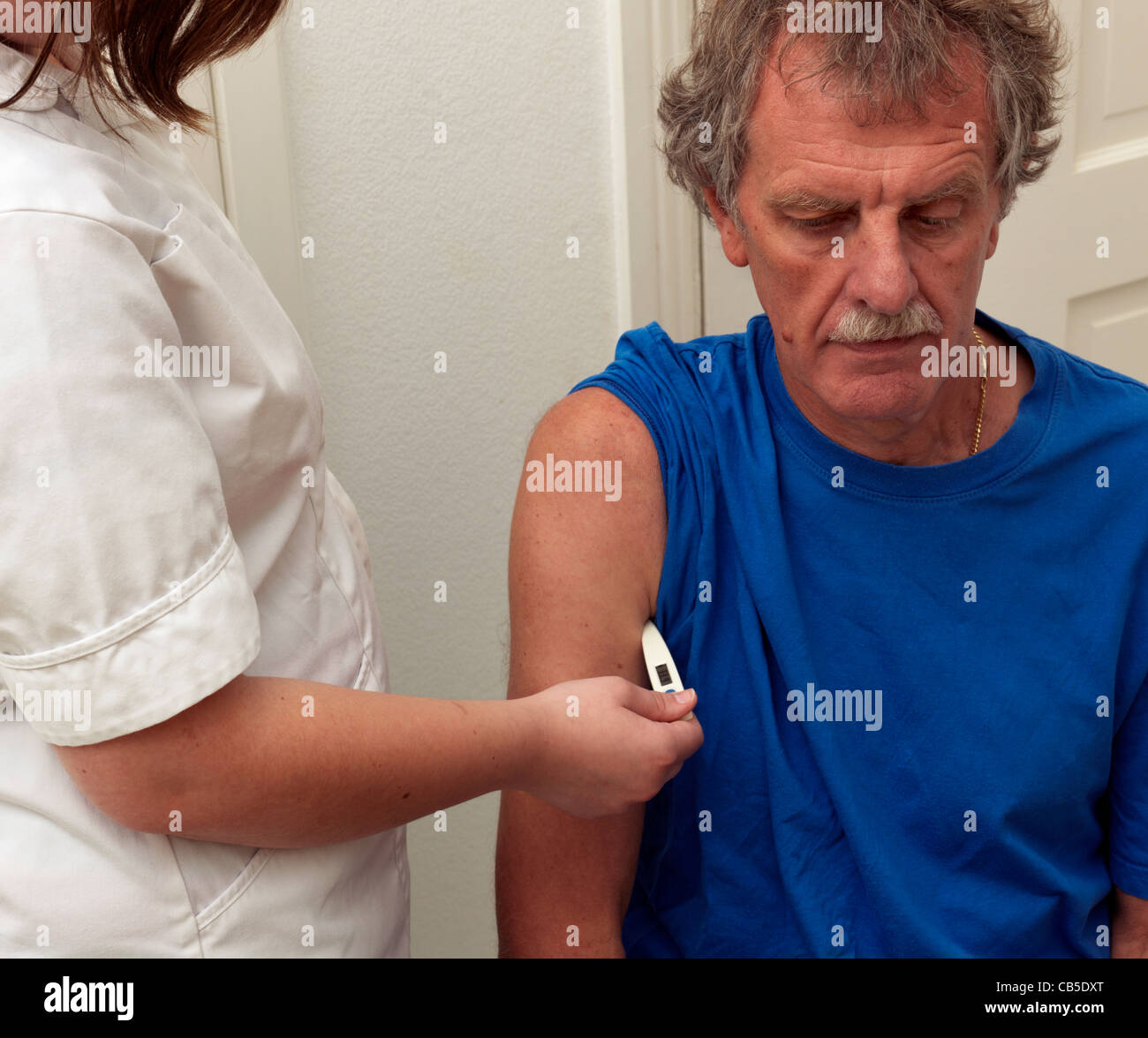 Krankenschwester Platzierung Digitalthermometer unter Arm des Patienten unter Temperatur Stockfoto