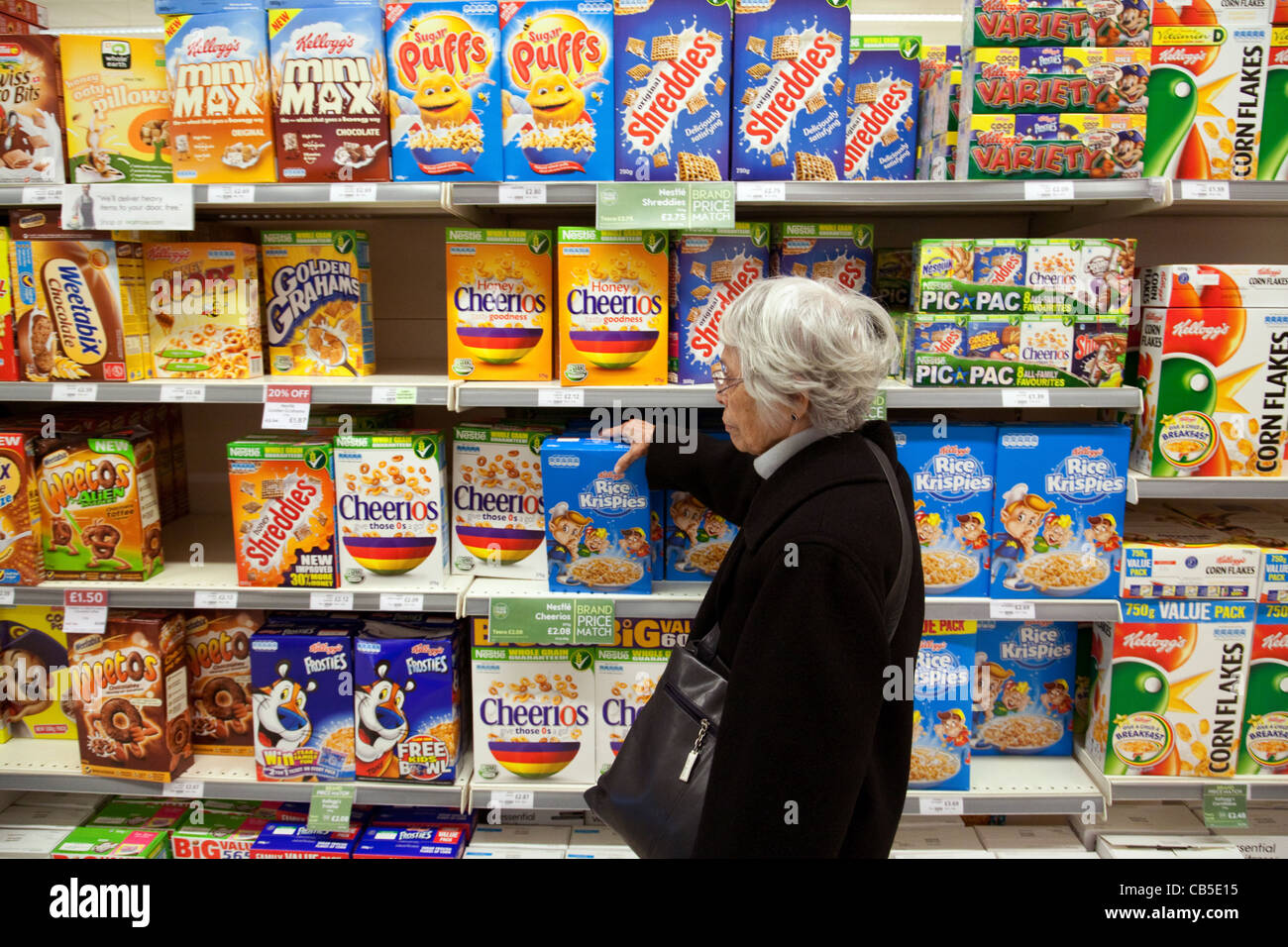 Ältere Frau kaufen Frühstück Getreide aus Supermarktregalen, UK Stockfoto
