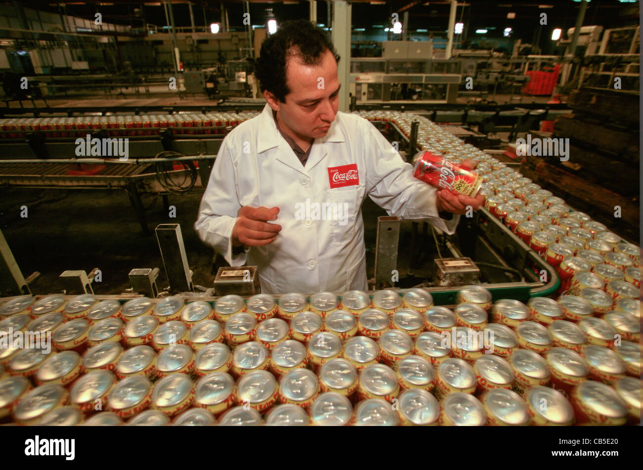 Ein Arbeiter inspiziert Dosen von Coca-Cola auf der Fertigungslinie an einer Abfüllanlage im Nahen Osten Stockfoto