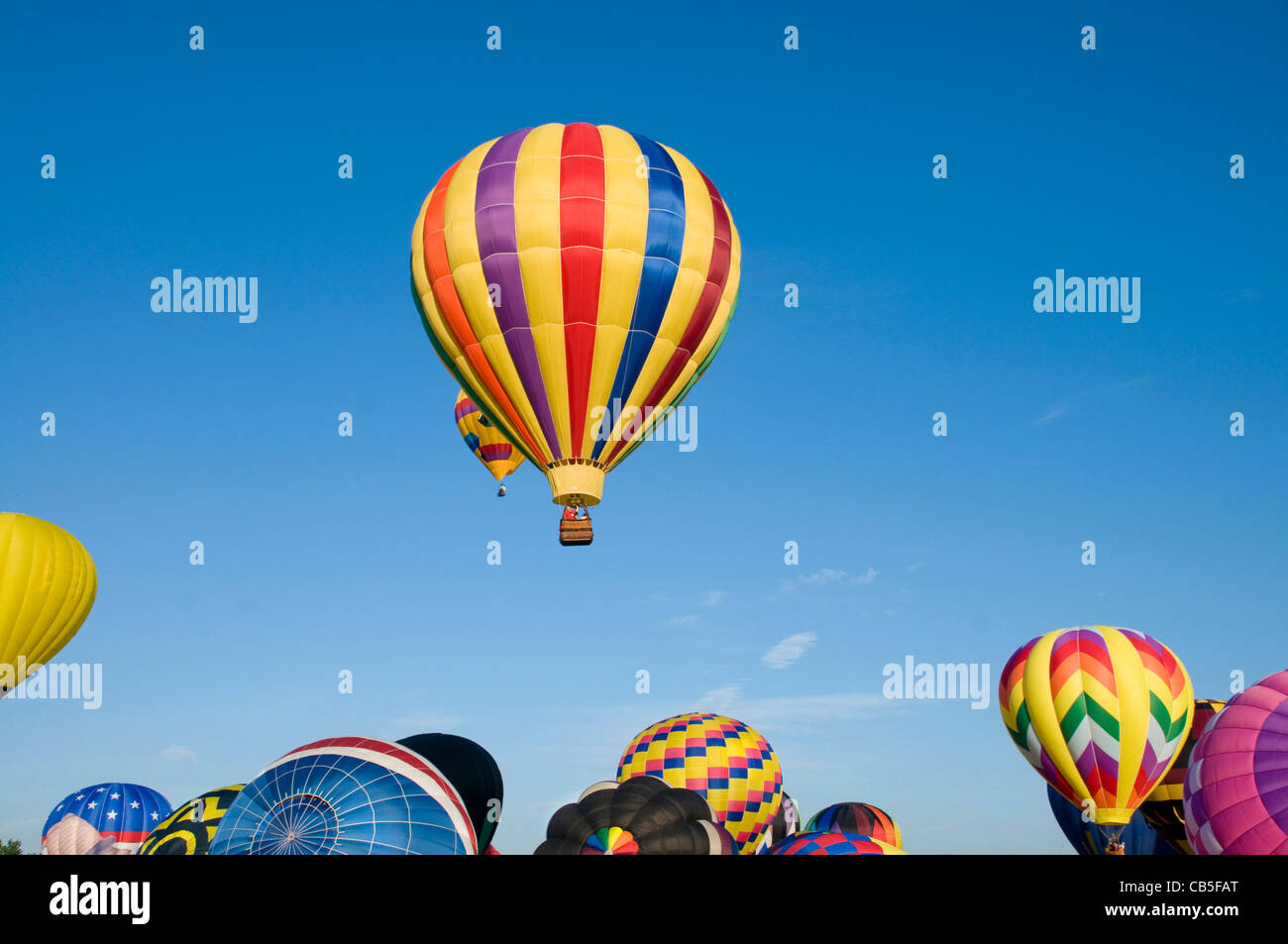 Heißluftballons über diejenigen auf dem Boden aufblasen aufsteigend Stockfoto