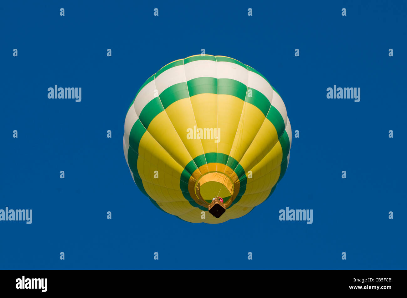Grün, weiß und gelb Heißluft-Ballon in der Luft, geschossen von unten Stockfoto